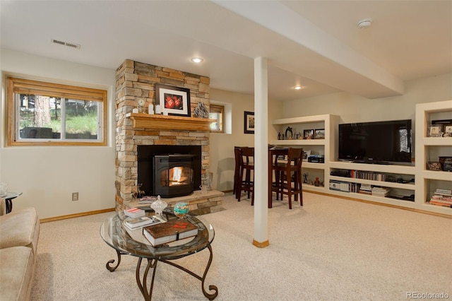 living room featuring visible vents, baseboards, carpet, built in features, and a stone fireplace