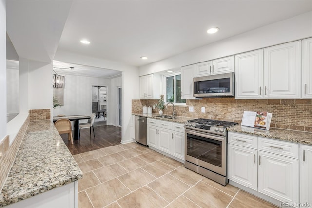 2644 S Krameria St, Denver, CO 80222 - kitchen with stainless steel appliances, a sink, white cabinets, light stone countertops, and recessed lighting