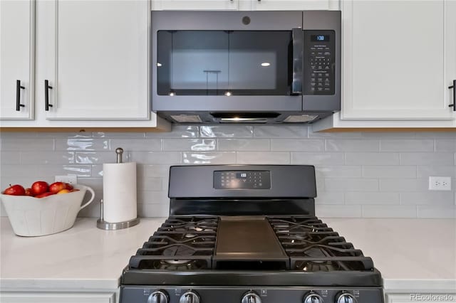 1369 E Witherspoon Dr, Elizabeth, CO 80107 - kitchen featuring black gas range, stainless steel microwave, white cabinets, and tasteful backsplash