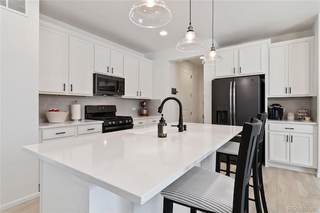 1369 E Witherspoon Dr, Elizabeth, CO 80107 - kitchen with black appliances, a sink, white cabinetry, tasteful backsplash, and a breakfast bar