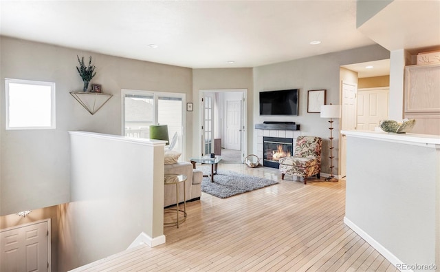 living room featuring a tile fireplace and light hardwood / wood-style floors