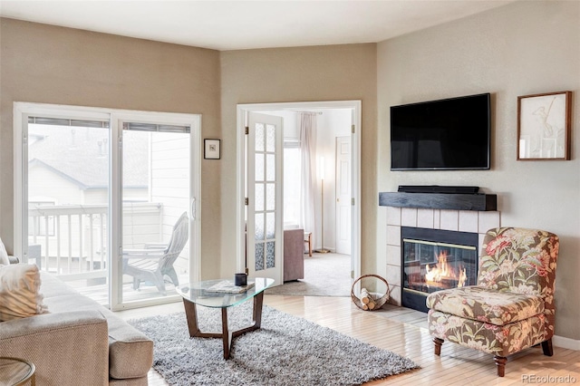 living room featuring wood-type flooring, plenty of natural light, and a tiled fireplace