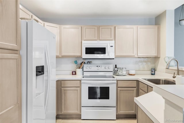 kitchen with light brown cabinetry, sink, light tile patterned floors, and white appliances