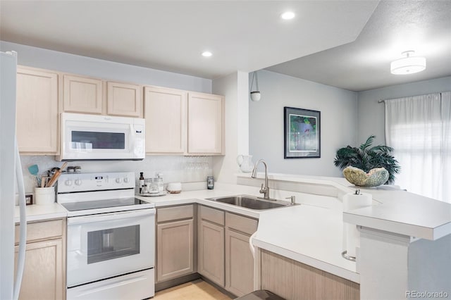 kitchen featuring kitchen peninsula, sink, light brown cabinetry, and white appliances