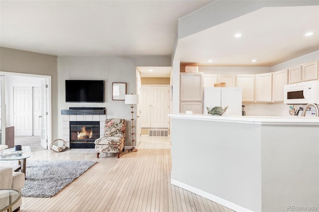 living room with sink, light wood-type flooring, and a fireplace