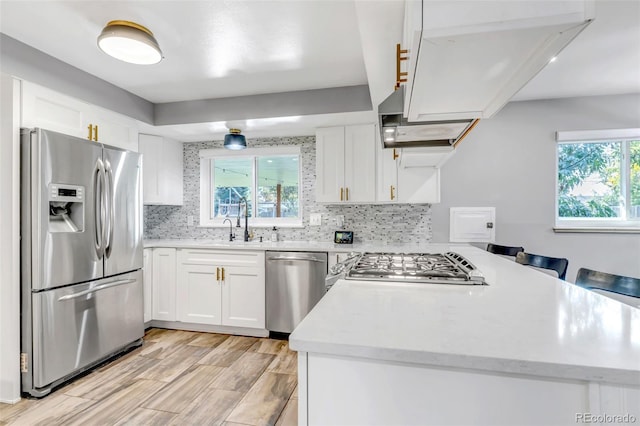 kitchen featuring backsplash, white cabinetry, stainless steel appliances, and a healthy amount of sunlight