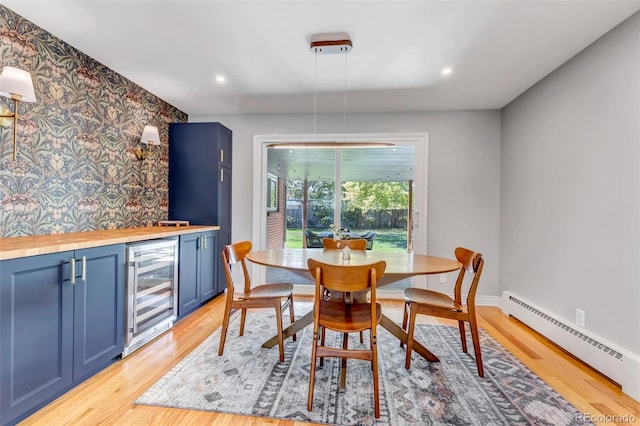 dining space featuring light hardwood / wood-style floors, a baseboard heating unit, and beverage cooler