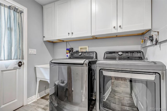 laundry room with cabinets, washer and dryer, and light wood-type flooring