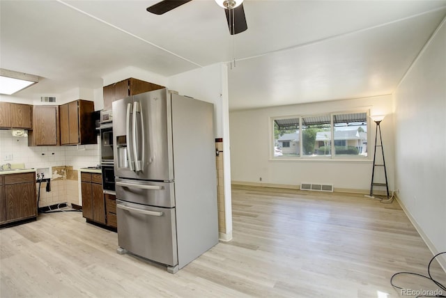 7291 Bryant St, Westminster, CO 80030 - kitchen with stainless steel appliances, light wood-style flooring, a ceiling fan, and decorative backsplash