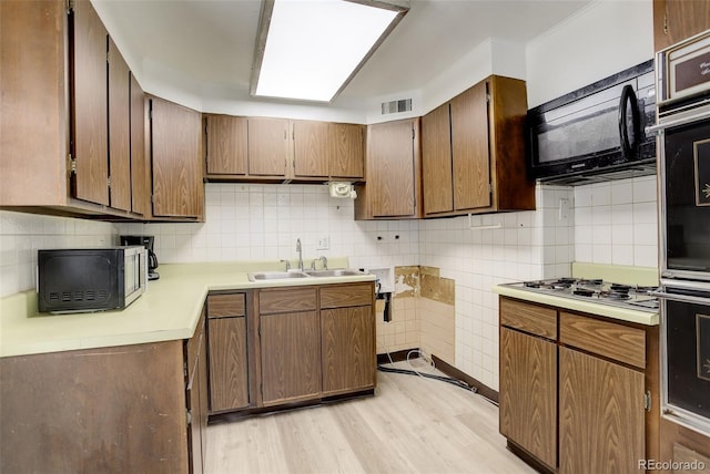 7291 Bryant St, Westminster, CO 80030 - kitchen featuring a sink, appliances with stainless steel finishes, light wood-style floors, light countertops, and backsplash