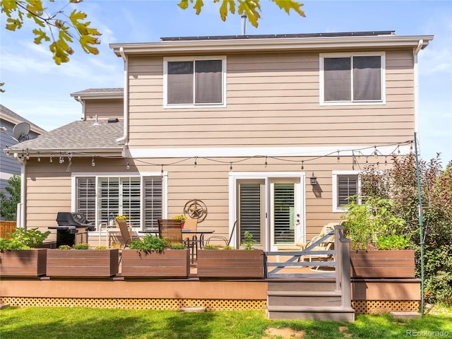 back of property featuring a shingled roof and a deck