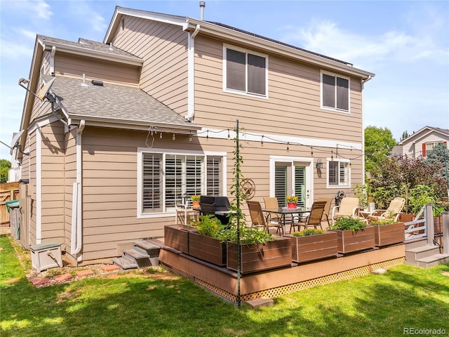 back of house featuring a deck, a yard, and a shingled roof