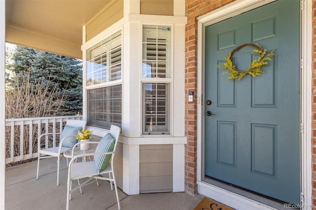 property entrance with a porch and brick siding