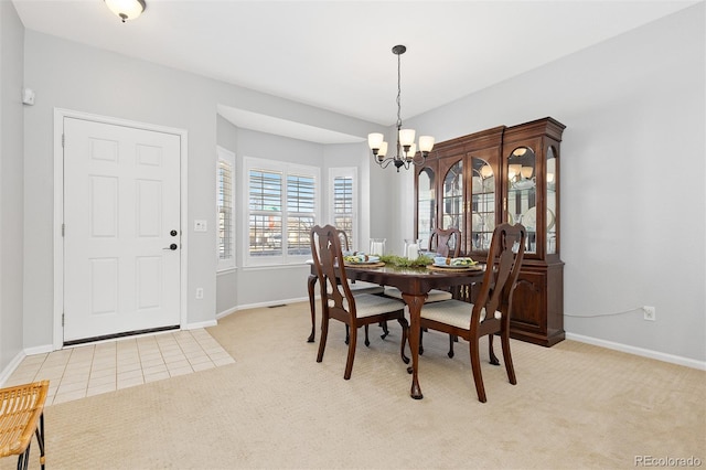 dining room featuring light carpet, a notable chandelier, and baseboards