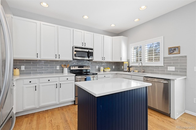 kitchen with stainless steel appliances, white cabinets, a sink, and light wood-style flooring