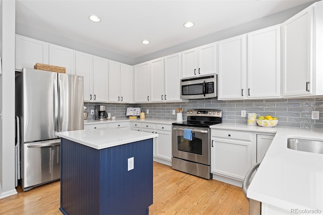 kitchen featuring stainless steel appliances, tasteful backsplash, light countertops, light wood-style flooring, and a kitchen island