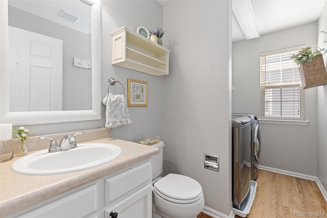 bathroom featuring toilet, separate washer and dryer, wood finished floors, vanity, and baseboards