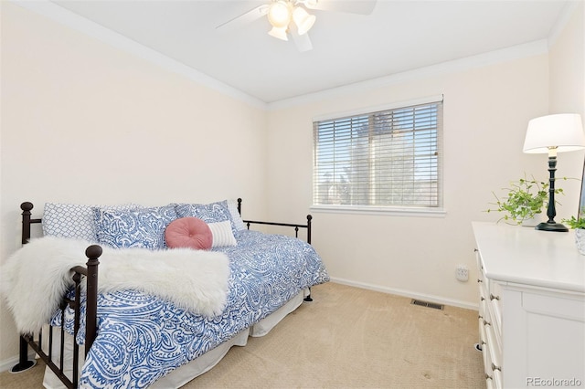 bedroom featuring baseboards, visible vents, a ceiling fan, light colored carpet, and crown molding