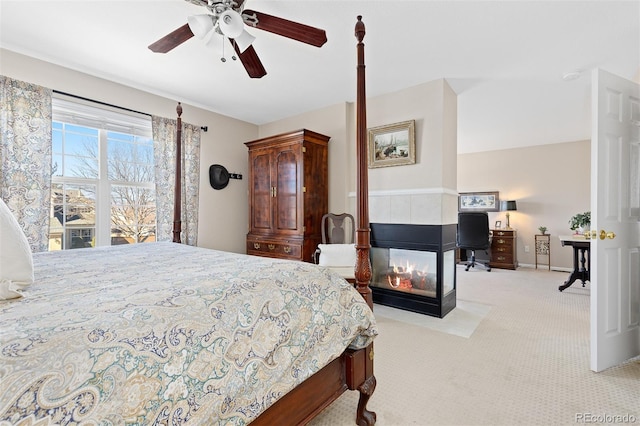 carpeted bedroom with ceiling fan and a multi sided fireplace