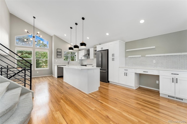 kitchen featuring appliances with stainless steel finishes, white cabinets, backsplash, hanging light fixtures, and a center island