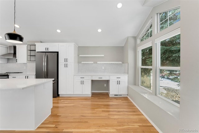 kitchen featuring decorative light fixtures, white cabinets, stainless steel fridge, decorative backsplash, and wall chimney exhaust hood