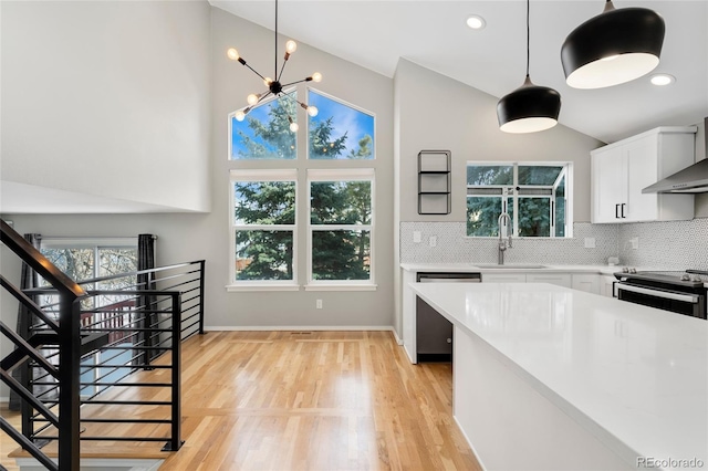 kitchen featuring stainless steel electric stove, lofted ceiling, sink, white cabinets, and hanging light fixtures