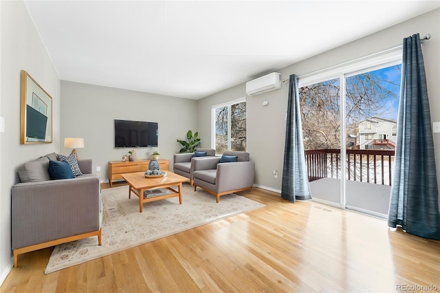 living room with a wall unit AC and light hardwood / wood-style floors