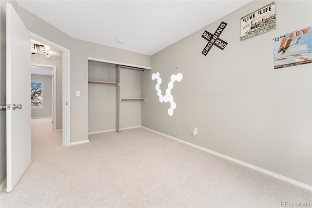 unfurnished bedroom with light colored carpet and a closet