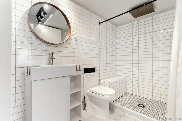 bathroom with tile walls, vanity, toilet, and tiled shower