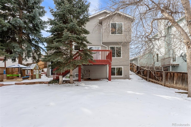 snow covered rear of property with a wooden deck