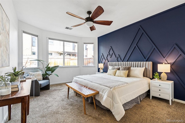 carpeted bedroom with visible vents, a ceiling fan, and baseboards