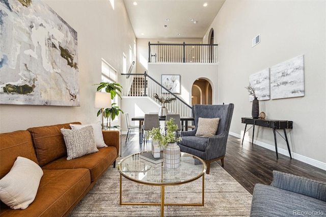 living area featuring wood finished floors, recessed lighting, arched walkways, baseboards, and stairs