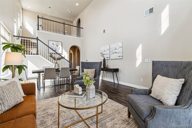 living area featuring arched walkways, visible vents, and wood finished floors