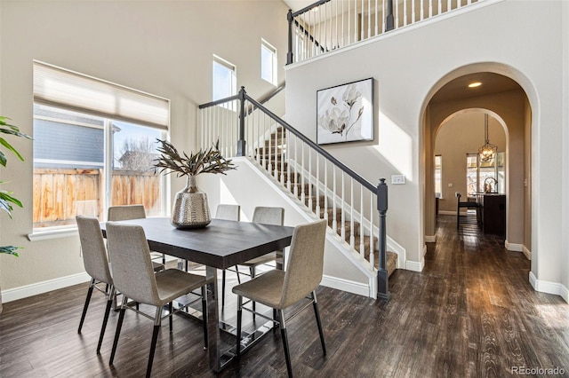 dining space with arched walkways, baseboards, and wood finished floors