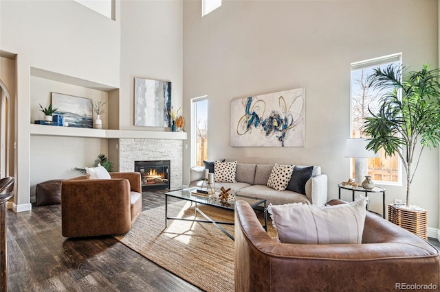 living area with plenty of natural light, a fireplace, baseboards, and dark wood-style flooring