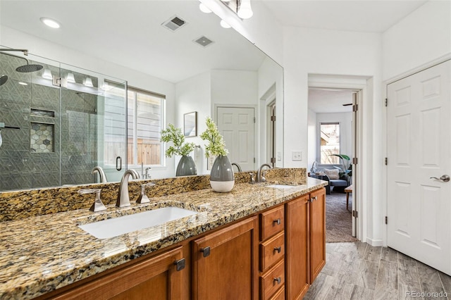 full bathroom with double vanity, visible vents, a shower stall, and a sink