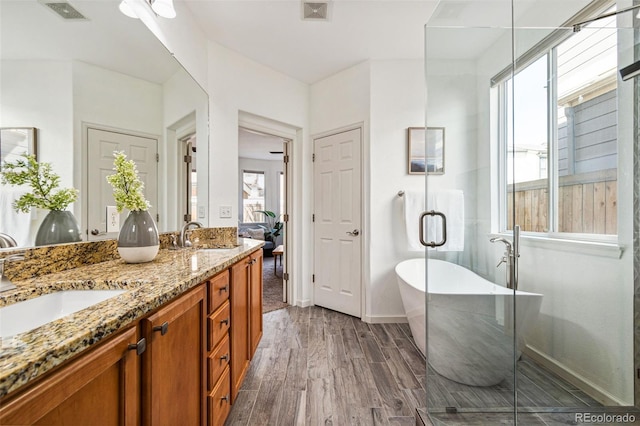 bathroom featuring a freestanding tub, visible vents, wood finished floors, and double vanity