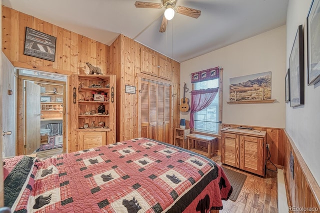 bedroom with wooden walls, ceiling fan, a closet, and light hardwood / wood-style flooring