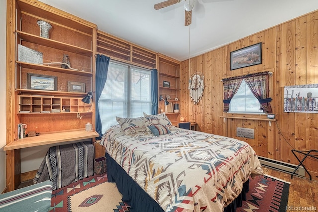 bedroom featuring ceiling fan, wooden walls, hardwood / wood-style floors, and a baseboard heating unit