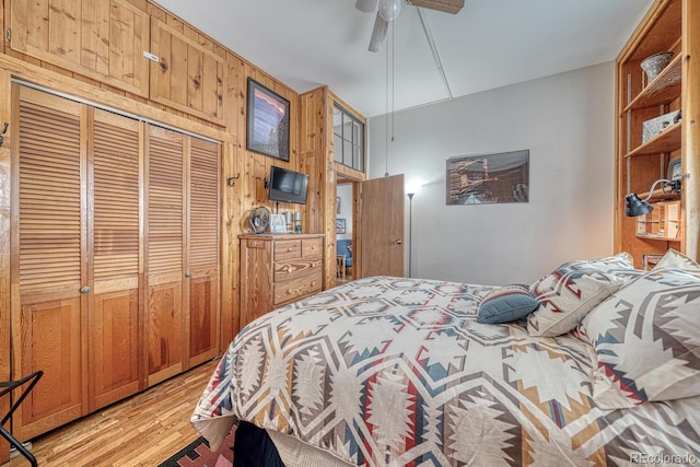 bedroom featuring ceiling fan, wood walls, a closet, and light hardwood / wood-style floors