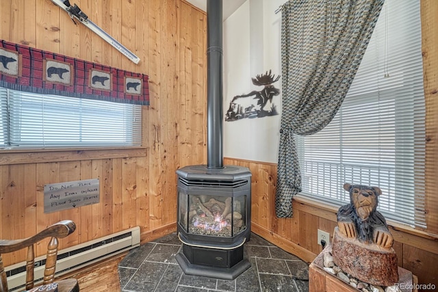 interior details with a baseboard radiator, hardwood / wood-style flooring, wooden walls, and a wood stove