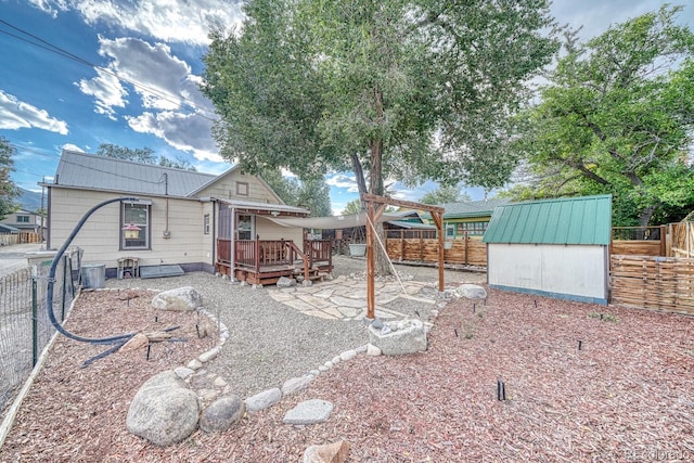 back of house featuring a shed, a patio, and a wooden deck