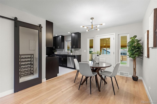 1310 E Amherst Ave, Englewood, CO 80113 - dining space featuring light wood-type flooring, a chandelier, and a barn door
