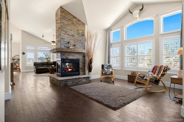 10044 E 146th Pl, Brighton, CO 80602 - living area featuring high vaulted ceiling, a stone fireplace, a ceiling fan, baseboards, and hardwood / wood-style flooring
