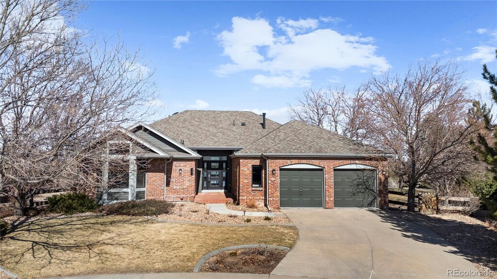 view of front of home featuring brick siding, an attached garage, roof with shingles, and driveway