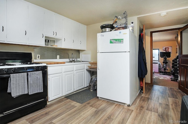 kitchen featuring white refrigerator, light hardwood / wood-style floors, black range, sink, and white cabinets