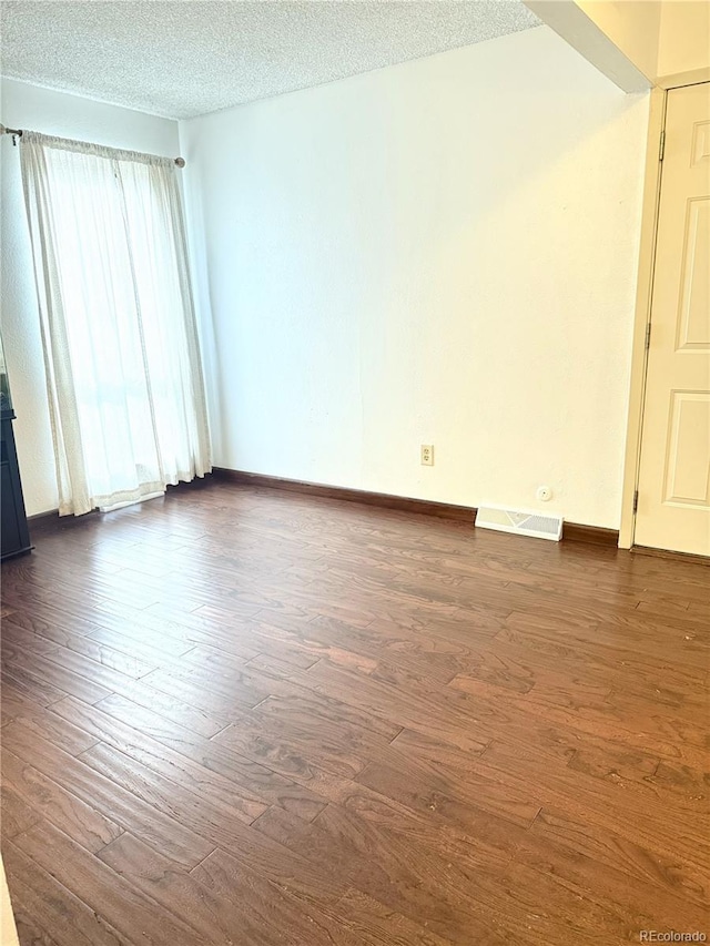 unfurnished room with dark wood-type flooring and a textured ceiling