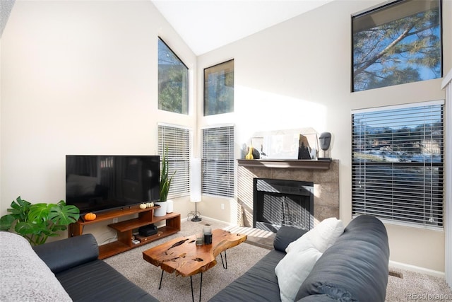 carpeted living room with high vaulted ceiling and a tiled fireplace