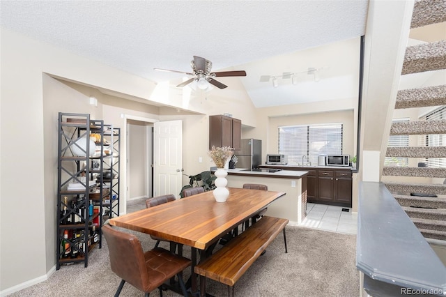 dining area with a textured ceiling, light colored carpet, vaulted ceiling, and ceiling fan