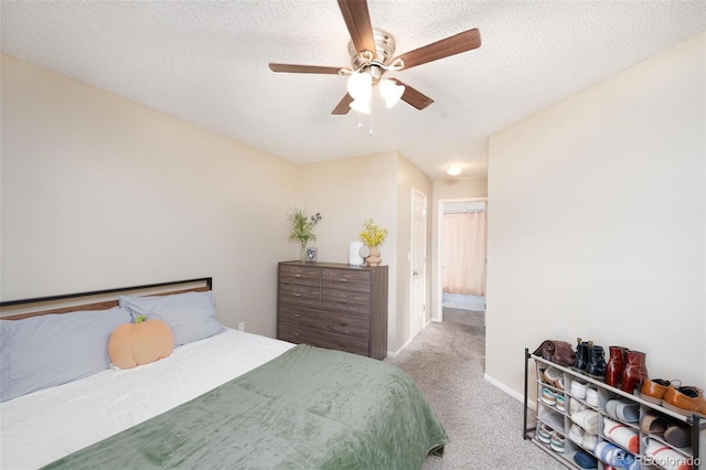 carpeted bedroom featuring ceiling fan and a textured ceiling